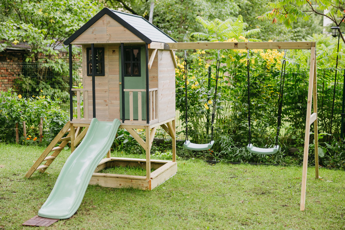 Children's playhouse with a slide and swing set in a garden
